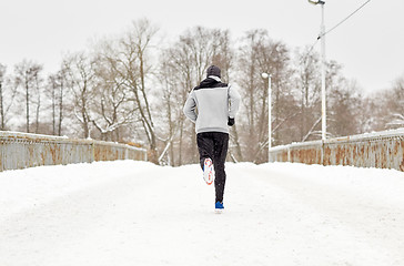 Image showing man running along snow covered winter bridge road