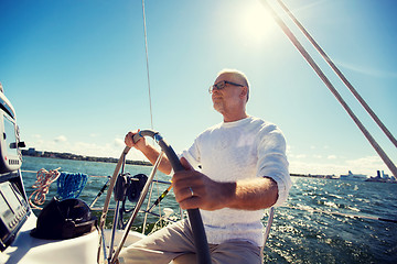 Image showing senior man at helm on boat or yacht sailing in sea