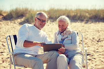 Image showing happy senior couple with tablet pc on summer beach