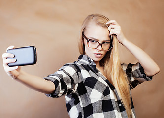 Image showing young pretty blond hipster girl making selfie on warm brown background, lifestyle people concept