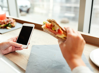 Image showing woman with smartphone and sandwich at restaurant