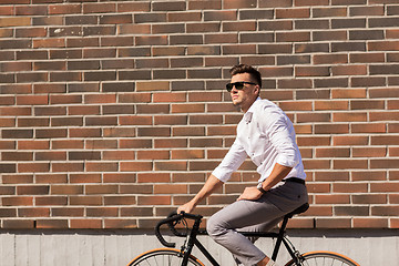 Image showing young man riding bicycle on city street