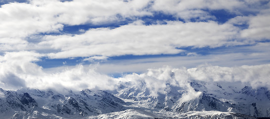 Image showing Panoramic view on snow mountains and sunlight cloudy sky at wint