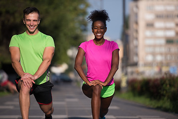 Image showing jogging couple warming up and stretching in the city