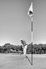 Image showing golf player hitting shot with club on course