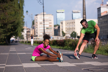 Image showing jogging couple warming up and stretching in the city