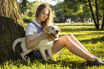 Image showing young attractive blond woman playing with her dog in green park at summer, lifestyle people concept