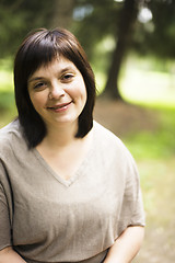 Image showing mature brunette fat woman in green garden, smiling, friendly wel