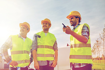 Image showing happy male builders in vests with walkie talkie