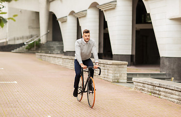 Image showing young man riding bicycle on city street