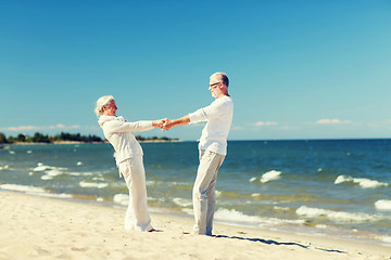 Image showing happy senior couple holding hands on summer beach