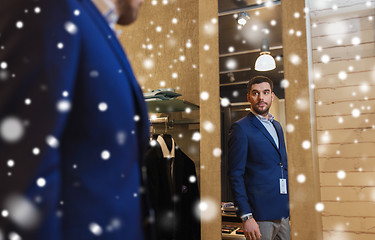 Image showing man trying jacket on at mirror in clothing store