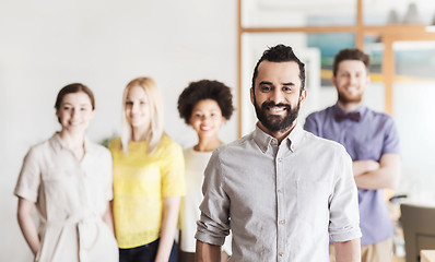 Image showing happy young man over creative team in office