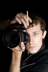 Image showing The young man - photographer behind work. Isolated on a black ba