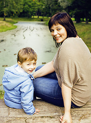 Image showing mature woman with little boy outside, mother with son in green p