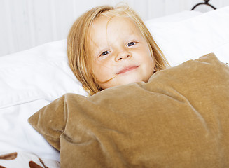 Image showing little cute blonde norwegian girl playing on sofa with pillows, 