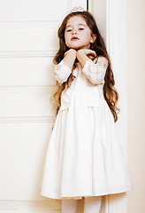 Image showing little cute girl at home, opening door well-dressed in white dre