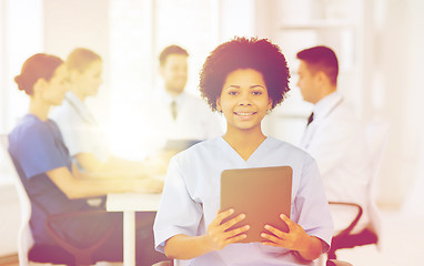 Image showing happy doctor with tablet pc over team at clinic