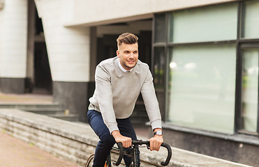 Image showing young man riding bicycle on city street