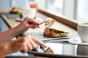 Image showing woman with tablet pc and panini sandwich at cafe