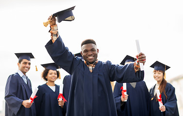 Image showing happy students in mortar boards with diplomas