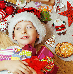 Image showing little cute kid in santas red hat with handmade gifts, toys vintage wooden, warm winter