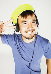 Image showing young asian man in hat and headphones listening music on white b