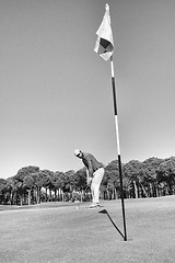 Image showing golf player hitting shot with club on course