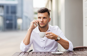 Image showing man with coffee calling on smartphone at city cafe