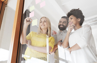 Image showing happy creative team writing on stickers at office