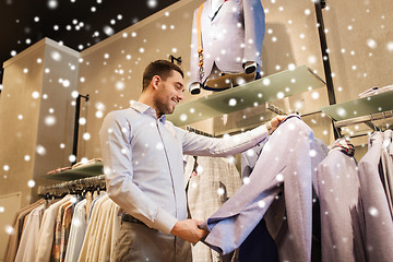 Image showing happy young man choosing clothes in clothing store