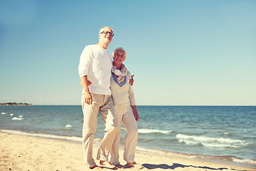 Image showing happy senior couple walking along summer beach