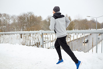 Image showing man running along snow covered winter bridge road