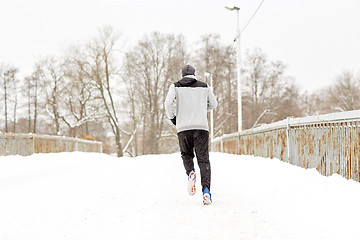 Image showing man running along snow covered winter bridge road