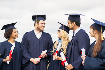 Image showing happy students in mortar boards with diplomas