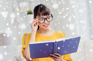 Image showing smiling young asian woman reading book at home