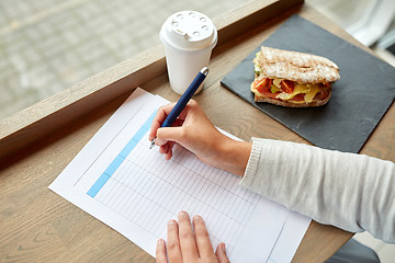 Image showing woman with paper form having lunch at cafe