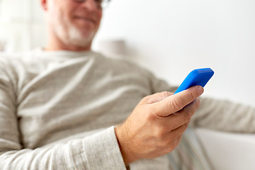 Image showing close up of old man texting on smartphone at home