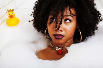 Image showing young afro-american teen girl laying in bath with foam, wearing 
