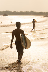 Image showing Silhouette of surfer on beach with surfboard.