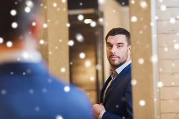 Image showing man trying jacket on at mirror in clothing store