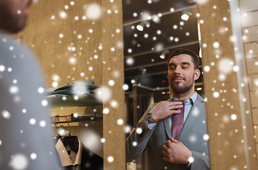 Image showing man trying tie on at mirror in clothing store