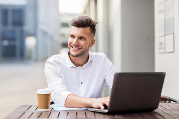 Image showing smiling man with laptop and coffee at city cafe