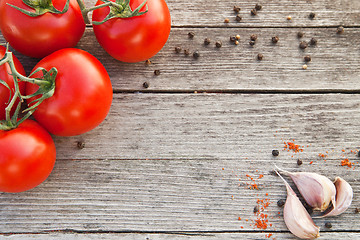 Image showing Red tomatoes with pepper and garlic on old wood