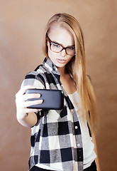 Image showing young pretty blond hipster girl making selfie on warm brown background, lifestyle people concept