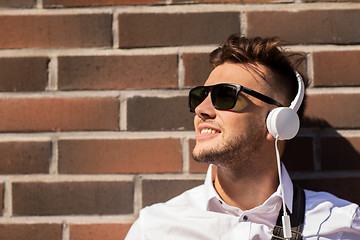 Image showing young man in headphones over brickwall