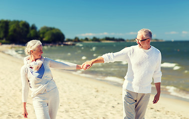 Image showing happy senior couple holding hands on summer beach