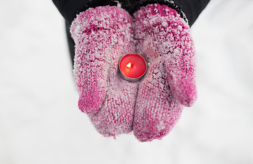 Image showing close up of hands in winter mittens holding candle