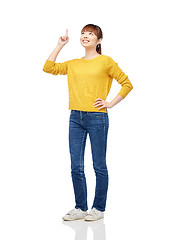 Image showing happy asian woman pointing finger up over white