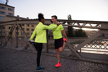 Image showing jogging couple warming up and stretching in the city